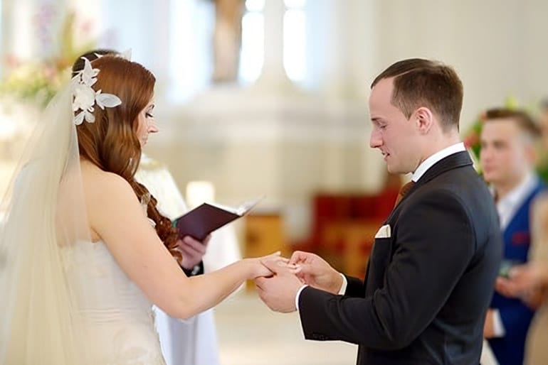 Couple se passannt l'anneau au doigt pendant une cérémonie religieuse